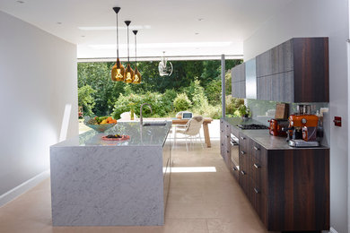 Foto på ett funkis kök, med en enkel diskho, glaspanel som stänkskydd, kalkstensgolv, en köksö, släta luckor, skåp i mörkt trä, bänkskiva i rostfritt stål, rostfria vitvaror och grått stänkskydd