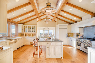 Expansive rural u-shaped enclosed kitchen in Boston with a belfast sink, shaker cabinets, white cabinets, blue splashback, stainless steel appliances, medium hardwood flooring, an island, brown floors, grey worktops, composite countertops and porcelain splashback.