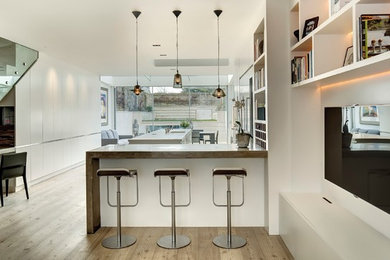 Photo of an expansive contemporary l-shaped open plan kitchen in London with flat-panel cabinets, white cabinets and an island.
