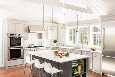 Inspiration for a mid-sized transitional l-shaped medium tone wood floor open concept kitchen remodel in Boston with an undermount sink, recessed-panel cabinets, gray cabinets, quartz countertops, white backsplash, subway tile backsplash, stainless steel appliances and an island