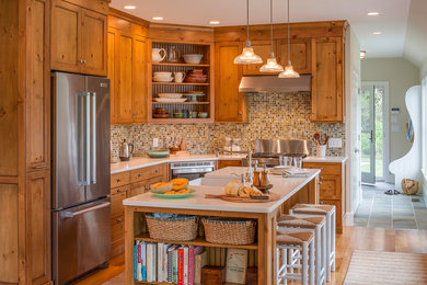 Inspiration for a small farmhouse l-shaped medium tone wood floor eat-in kitchen remodel in Boston with a farmhouse sink, recessed-panel cabinets, medium tone wood cabinets, quartz countertops, multicolored backsplash, glass tile backsplash, stainless steel appliances and an island