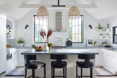 Eat-in kitchen - large country u-shaped light wood floor, beige floor, shiplap ceiling and vaulted ceiling eat-in kitchen idea in New York with a farmhouse sink, flat-panel cabinets, white cabinets, quartz countertops, white backsplash, quartz backsplash, stainless steel appliances, an island and gray countertops