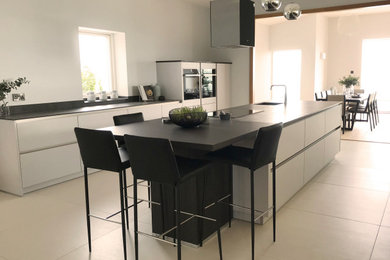 Zweizeilige, Große Moderne Wohnküche mit flächenbündigen Schrankfronten, weißen Schränken und Kücheninsel in Devon