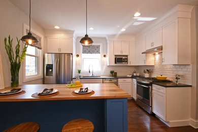 Mid-sized transitional l-shaped medium tone wood floor eat-in kitchen photo in Chicago with an undermount sink, shaker cabinets, white cabinets, white backsplash, stainless steel appliances, an island, wood countertops and ceramic backsplash