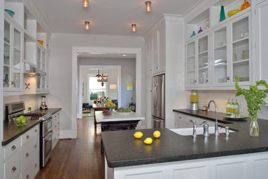 Example of a classic kitchen design in Houston with glass-front cabinets, stainless steel appliances and a farmhouse sink