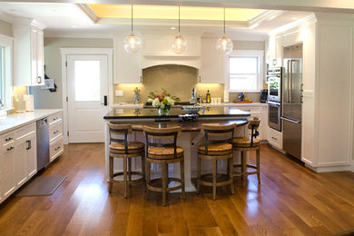 Eat-in kitchen - large traditional u-shaped light wood floor eat-in kitchen idea in San Francisco with an undermount sink, shaker cabinets, white cabinets, limestone countertops, beige backsplash, glass tile backsplash, stainless steel appliances and an island