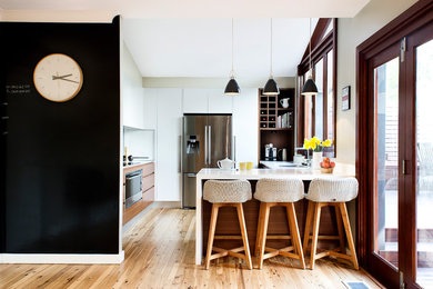 Mittelgroße Moderne Küche in U-Form mit Unterbauwaschbecken, flächenbündigen Schrankfronten, weißen Schränken, Küchengeräten aus Edelstahl und braunem Holzboden in Sydney