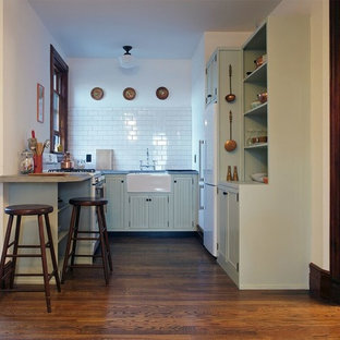 Design ideas for a large victorian u-shaped open plan kitchen in New York with a farmhouse sink, louvered cabinets, green cabinets, wood benchtops, white splashback, stone tile splashback, white appliances, dark hardwood floors and a peninsula.