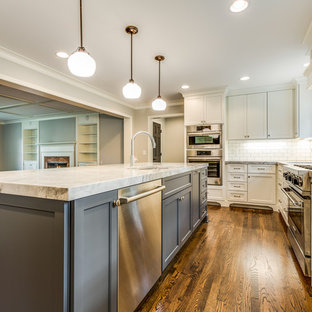 Large farmhouse open concept kitchen ideas - Example of a large country l-shaped medium tone wood floor and brown floor open concept kitchen design in Cleveland with an undermount sink, recessed-panel cabinets, white cabinets, granite countertops, white backsplash, subway tile backsplash, stainless steel appliances, an island and multicolored countertops