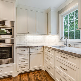 Large farmhouse open concept kitchen remodeling - Example of a large farmhouse l-shaped medium tone wood floor and brown floor open concept kitchen design in Cleveland with an undermount sink, recessed-panel cabinets, white cabinets, granite countertops, white backsplash, subway tile backsplash, stainless steel appliances, an island and multicolored countertops