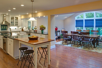 Example of a large classic u-shaped light wood floor eat-in kitchen design in Baltimore with white cabinets, granite countertops, white backsplash, ceramic backsplash, stainless steel appliances, an island, an undermount sink and raised-panel cabinets