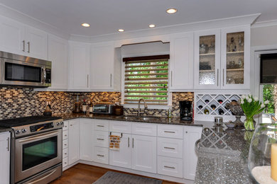 Exempel på ett mellanstort klassiskt kök, med en dubbel diskho, luckor med infälld panel, vita skåp, bänkskiva i kvarts, flerfärgad stänkskydd, rostfria vitvaror, mellanmörkt trägolv och en halv köksö