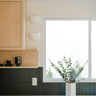 Mid-sized scandinavian open concept kitchen inspiration - Example of a mid-sized danish l-shaped concrete floor and white floor open concept kitchen design in Los Angeles with beige cabinets, green backsplash, ceramic backsplash, white appliances, an island and white countertops