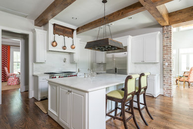 Eat-in kitchen - mid-sized traditional l-shaped dark wood floor and brown floor eat-in kitchen idea in Houston with raised-panel cabinets, white cabinets, white backsplash, stone slab backsplash, stainless steel appliances, an island, a farmhouse sink and marble countertops