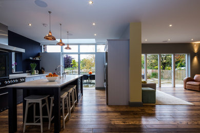 Inspiration for a contemporary kitchen in Cambridgeshire with a belfast sink, shaker cabinets, blue cabinets, granite worktops, stainless steel appliances, dark hardwood flooring, an island and brown floors.