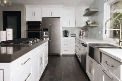 Eat-in kitchen - mid-sized contemporary l-shaped dark wood floor and brown floor eat-in kitchen idea in Orange County with a farmhouse sink, shaker cabinets, white cabinets, quartz countertops, glass tile backsplash, stainless steel appliances and an island