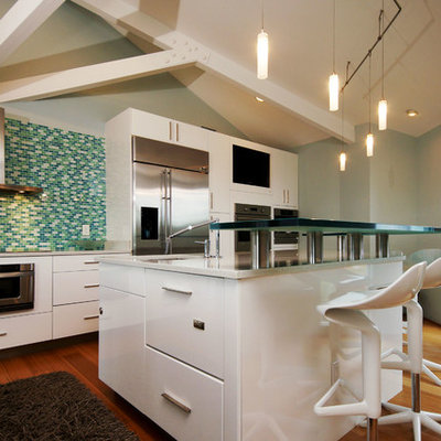 Example of a mid-sized beach style single-wall bamboo floor eat-in kitchen design in New Orleans with flat-panel cabinets, white cabinets, glass countertops, ceramic backsplash and stainless steel appliances