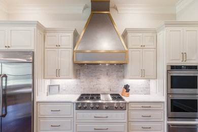 Kitchen - traditional u-shaped kitchen idea in New Orleans with raised-panel cabinets and an island