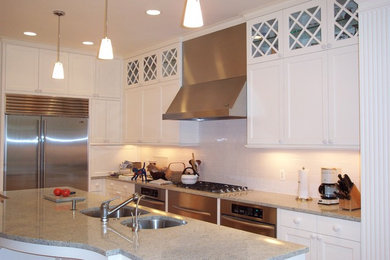 Inspiration for a mid-sized transitional l-shaped medium tone wood floor and brown floor eat-in kitchen remodel in Chicago with white backsplash, an undermount sink, recessed-panel cabinets, white cabinets, subway tile backsplash, stainless steel appliances, an island and granite countertops