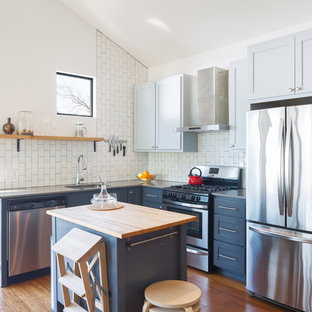 Photo of a small transitional l-shaped kitchen in Austin with an undermount sink, soapstone benchtops, white splashback, subway tile splashback, stainless steel appliances, medium hardwood floors, with island, shaker cabinets, blue cabinets and orange floor.