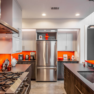 Inspiration for a mid-sized contemporary u-shaped concrete floor and gray floor eat-in kitchen remodel in New Orleans with a single-bowl sink, flat-panel cabinets, dark wood cabinets, quartz countertops, orange backsplash, glass tile backsplash, stainless steel appliances, an island and black countertops