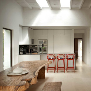 Immagine di una cucina mediterranea di medie dimensioni con ante lisce, ante bianche, elettrodomestici in acciaio inossidabile, penisola e pavimento con piastrelle in ceramica