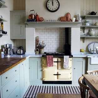 Photo of a mid-sized eclectic l-shaped eat-in kitchen in Nashville with a farmhouse sink, flat-panel cabinets, green cabinets, marble benchtops, white splashback, subway tile splashback, coloured appliances and ceramic floors.