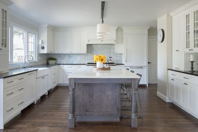 Eat-in kitchen - large transitional u-shaped light wood floor and brown floor eat-in kitchen idea in Denver with a farmhouse sink, shaker cabinets, white cabinets, quartz countertops, white backsplash, marble backsplash, paneled appliances and two islands