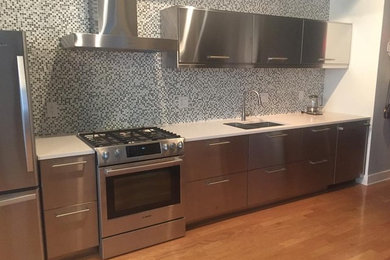 Mid-sized trendy galley open concept kitchen photo in New York with an undermount sink, flat-panel cabinets, stainless steel cabinets, quartz countertops, multicolored backsplash, mosaic tile backsplash, stainless steel appliances and no island