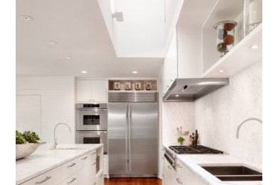 Foto på ett funkis kök, med en undermonterad diskho, släta luckor, vita skåp, granitbänkskiva, vitt stänkskydd, stänkskydd i sten, rostfria vitvaror, ljust trägolv och en köksö