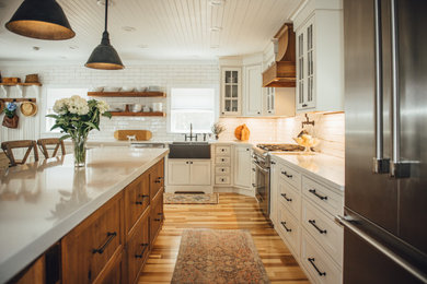 Eat-in kitchen - country l-shaped medium tone wood floor and wood ceiling eat-in kitchen idea with a farmhouse sink, beaded inset cabinets, white cabinets, quartz countertops, white backsplash, porcelain backsplash, stainless steel appliances, an island and white countertops
