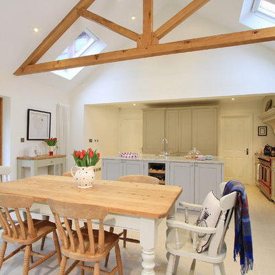 Large elegant porcelain tile eat-in kitchen photo in Hampshire with a farmhouse sink, shaker cabinets, gray cabinets, granite countertops, ceramic backsplash, colored appliances and an island