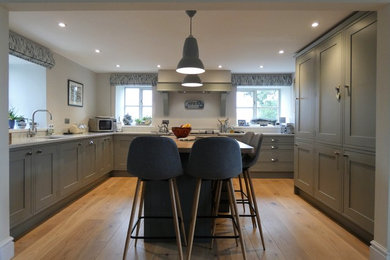 Inspiration pour une grande cuisine ouverte encastrable rustique en U avec un évier intégré, un placard à porte shaker, un plan de travail en quartz, un sol en bois brun et îlot.