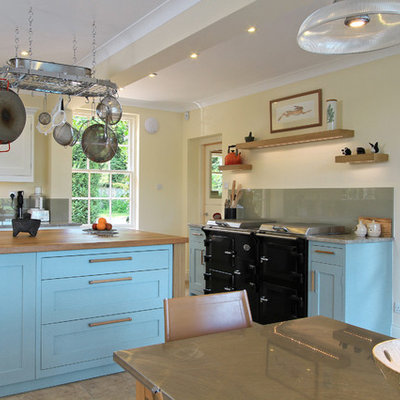 Elegant eat-in kitchen photo in Hampshire with wood countertops, shaker cabinets, blue cabinets and black appliances