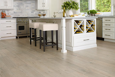 Inspiration for a large rustic l-shaped light wood floor eat-in kitchen remodel in Louisville with white cabinets, gray backsplash, ceramic backsplash, stainless steel appliances and an island