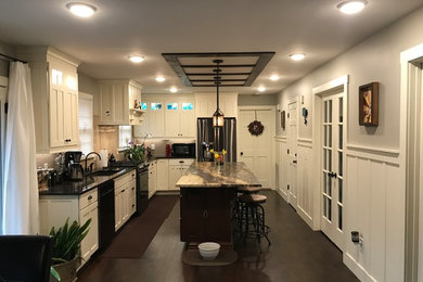 Inspiration for a large craftsman l-shaped dark wood floor and brown floor kitchen remodel in Nashville with an undermount sink, shaker cabinets, white cabinets, granite countertops, stainless steel appliances and an island