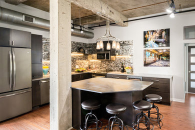 Inspiration for a mid-sized industrial l-shaped medium tone wood floor kitchen remodel in Detroit with flat-panel cabinets, dark wood cabinets, multicolored backsplash, stainless steel appliances and an island