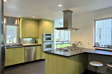 Inspiration för mellanstora moderna kök, med en undermonterad diskho, släta luckor, gröna skåp, granitbänkskiva, stänkskydd med metallisk yta, stänkskydd i metallkakel, rostfria vitvaror, klinkergolv i keramik och en halv köksö