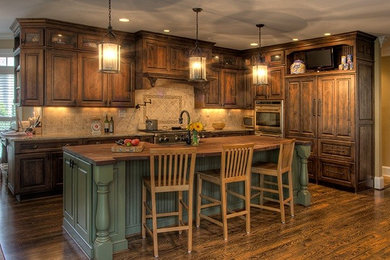 Example of a large classic l-shaped medium tone wood floor eat-in kitchen design in Atlanta with a farmhouse sink, raised-panel cabinets, dark wood cabinets, granite countertops, beige backsplash, stone tile backsplash, paneled appliances and an island