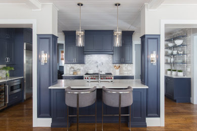 Inspiration for a mid-sized transitional u-shaped medium tone wood floor and brown floor open concept kitchen remodel in St Louis with an undermount sink, flat-panel cabinets, blue cabinets, quartz countertops, gray backsplash, ceramic backsplash, paneled appliances, an island and white countertops
