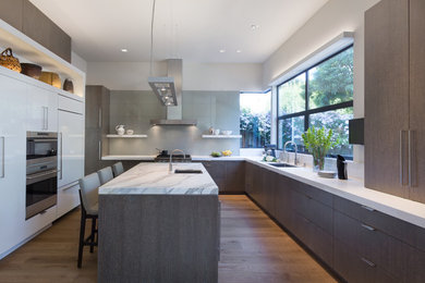 Moderne Küche in grau-weiß in U-Form mit Unterbauwaschbecken, flächenbündigen Schrankfronten, dunklen Holzschränken, Küchenrückwand in Grau, Küchengeräten aus Edelstahl, braunem Holzboden, Kücheninsel und Marmor-Arbeitsplatte in San Francisco