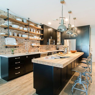 Inspiration for a small industrial kitchen in Miami with a double-bowl sink, shaker cabinets, black cabinets, quartz benchtops, stainless steel appliances, vinyl floors and with island.