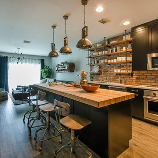 Design ideas for a small industrial kitchen in Miami with a double-bowl sink, shaker cabinets, black cabinets, quartz benchtops, terra-cotta splashback, stainless steel appliances, vinyl floors and with island.