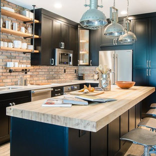 Small industrial kitchen appliance - Small urban vinyl floor kitchen photo in Miami with a double-bowl sink, shaker cabinets, black cabinets, quartz countertops, terra-cotta backsplash, stainless steel appliances and an island