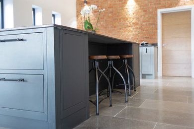 Photo of a medium sized industrial l-shaped kitchen/diner in Other with limestone flooring, an island, grey floors and black worktops.