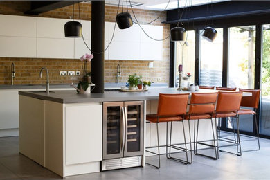 Inspiration for a medium sized urban single-wall kitchen in London with a built-in sink, flat-panel cabinets, white cabinets, concrete worktops, brick splashback, porcelain flooring, an island, grey floors, grey worktops, beige splashback and stainless steel appliances.