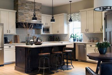 Example of a classic l-shaped medium tone wood floor eat-in kitchen design in Houston with a farmhouse sink, shaker cabinets, gray backsplash, subway tile backsplash, stainless steel appliances and an island