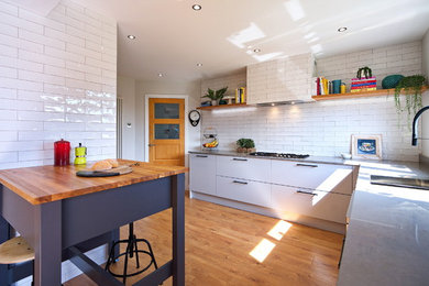Inspiration for a medium sized industrial l-shaped kitchen/diner in Other with a built-in sink, flat-panel cabinets, grey cabinets, quartz worktops, white splashback, ceramic splashback, stainless steel appliances, laminate floors, an island, brown floors and grey worktops.