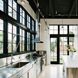 Example of a large urban single-wall light wood floor and brown floor eat-in kitchen design in Columbus with an integrated sink, flat-panel cabinets, stainless steel cabinets, stainless steel countertops, white backsplash, stainless steel appliances, an island and white countertops