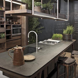 Mid-sized urban galley concrete floor and gray floor eat-in kitchen photo in Columbus with an integrated sink, flat-panel cabinets, light wood cabinets, concrete countertops, stainless steel appliances, an island and black countertops